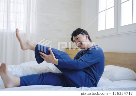 一名 20 多歲的男子在床上腿抽筋 136334712