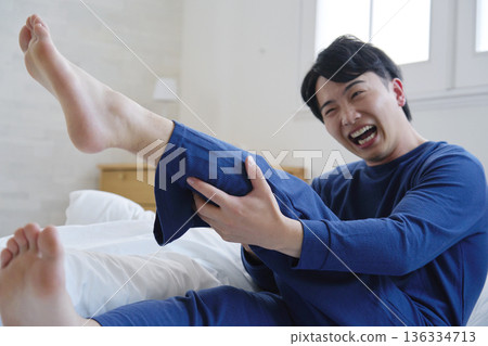 一名 20 多歲的男子在床上腿抽筋 136334713