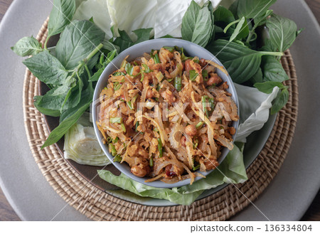 Homemade fermented pork and Thai crispy fried rice salad, featuring crispy fried rice balls served with wild betel leaves (cha-plu leaves), ginger, peanuts, and lime juice. 136334804
