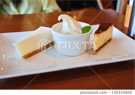A dessert plate featuring two types of cheesecake and soft serve ice cream 136334808