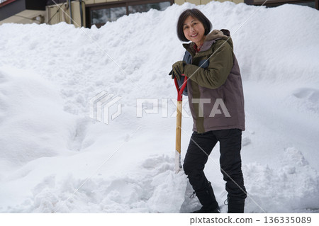 A woman at a loss with a shovel in heavy snow A woman at a loss with a shovel in heavy snow 136335089