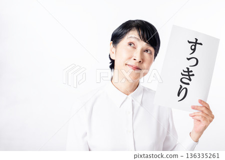一位面帶笑容的老婦人手裡拿著一張紙，上面工整地寫著一些指示。 136335261