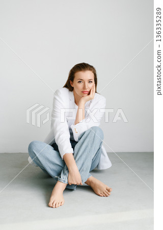 Relaxed Woman Sitting On Floor In Minimalist Room 136335289