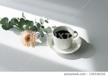 Coffee and gerberas on a white table with slanting light Coffee and gerberas on a white table with slanting light 136336102