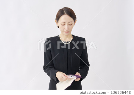 一位身著喪服的女子從一塊布中取出慰問禮物，白色背景 136336448