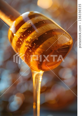 Macro shot of melting pure honey with wooden dipper and golden glitter background 136336535