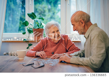 Senior couple solving jigsaw puzzle together at home. 136336665