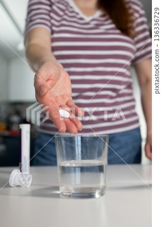 Person Prepares to Drop a Tablet Into a Glass of Water in a Home Setting Person Prepares to Drop a Tablet Into a Glass of Water in a Home Setting 136336729