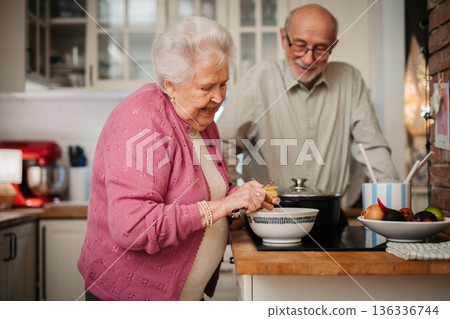 Elderly couple making dinner together in kitchen. 136336744