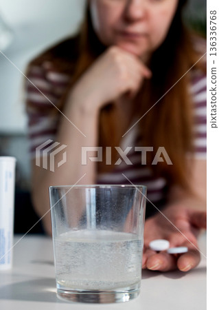 Woman Prepares to Take Effervescent Tablet With Glass of Water 136336768