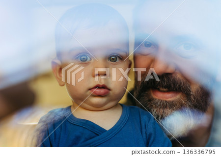 Father with little toddler son looking out of window. Father with little toddler son looking out of window. 136336795