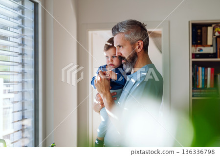 Father with little toddler son looking out of window. 136336798