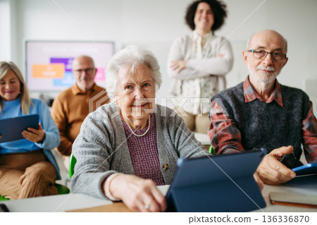 Elderly woman learning digital skills with tutor help. 136336870