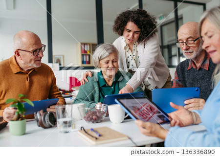 Volunteer teaching seniors how to recognize fake news on digital tablet. Volunteer teaching seniors how to recognize fake news on digital tablet. 136336890