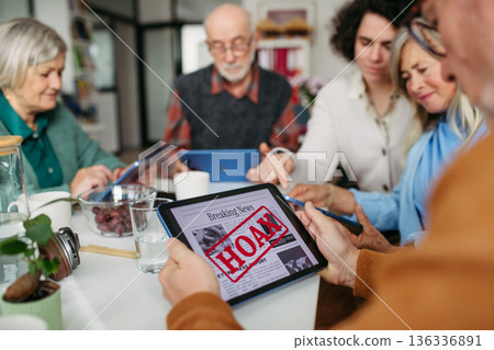 Volunteer teaching seniors how to recognize fake news on digital tablet. Volunteer teaching seniors how to recognize fake news on digital tablet. 136336891