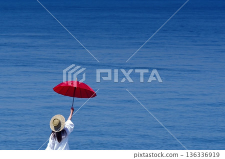 A woman holding a red parasol at the beach A woman holding a red parasol at the beach 136336919
