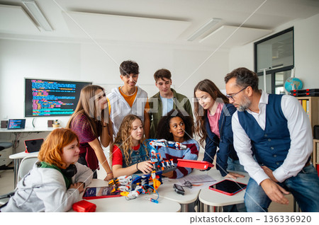 Diverse high school team building robotic arms during science class. 136336920