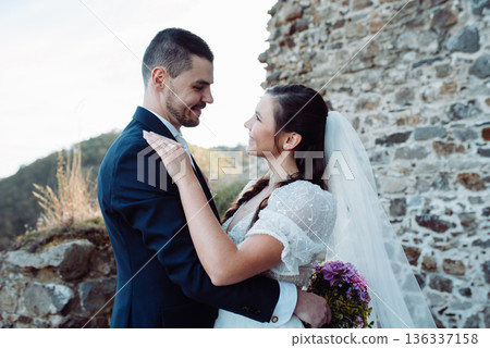Portrait of beautiful wedding couple hugging, standing outside near ruins. Portrait of beautiful wedding couple hugging, standing outside near ruins. 136337158