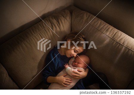 Young girl holding newborn sister. Tender sibling moment. 136337192