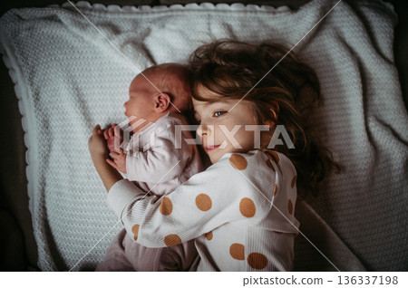 Young girl holding newborn sister. Tender sibling moment. Young girl holding newborn sister. Tender sibling moment. 136337198