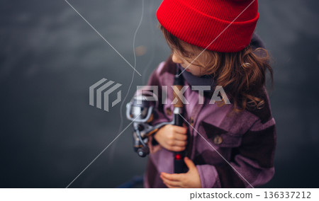 Child enjoying fishing outdoors during cold season. Child enjoying fishing outdoors during cold season. 136337212