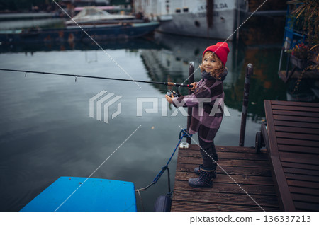 Child enjoying fishing outdoors during cold season. Child enjoying fishing outdoors during cold season. 136337213