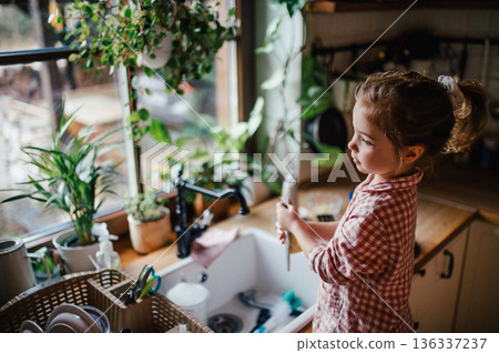 Independent child doing dishes at home. 136337237
