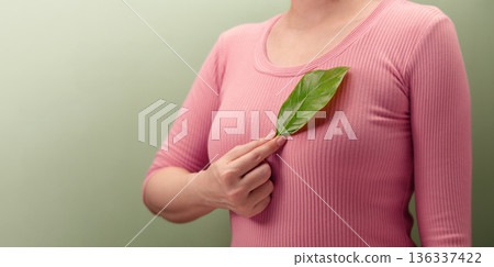 Woman holding green leaf over her Chest, Heart. Environmental awareness 136337422