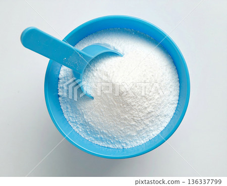 Professional service ads. Pile of powdered detergent in blue plastic container with a measuring spoon on a white background. Home washing and cleaning. Professional service ads. Pile of powdered detergent in blue plastic container with a measuring spoon on a white background. Home washing and cleaning. 136337799
