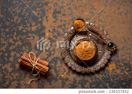 Ground Spice On Decorative Plate With Cinnamon Sticks Beside It 136337832