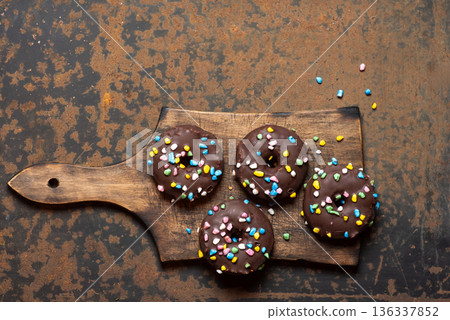 Charming Chocolate Donuts With Sprinkles On Rustic Cutting Board Charming Chocolate Donuts With Sprinkles On Rustic Cutting Board 136337852