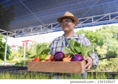 Farmer holding wooden box full of fresh vegetables.  136338027