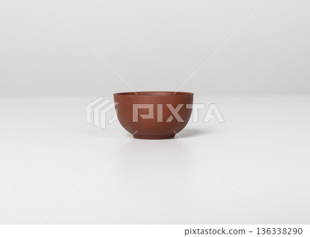Small ceramic bowl with a rounded shape and smooth matte surface placed on a light neutral Small ceramic bowl with a rounded shape and smooth matte surface placed on a light neutral 136338290