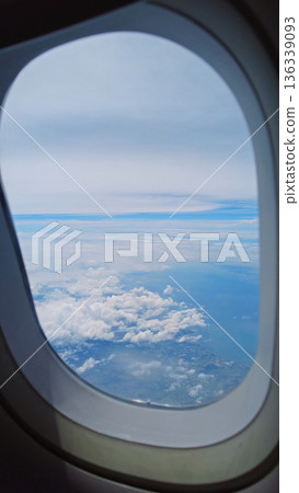 View from airplane window showing wing over clouds 136339093