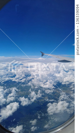 View from airplane window showing wing over clouds View from airplane window showing wing over clouds 136339094