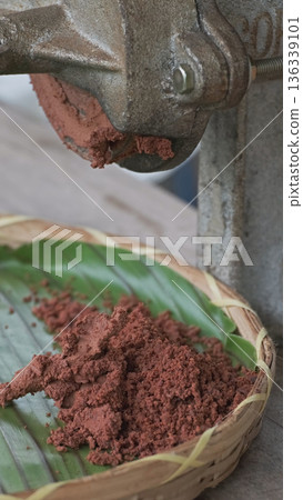 Cocoa maker grinding cocoa beans into chocolate 136339101