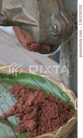 Cocoa maker grinding cocoa beans into chocolate 136339102