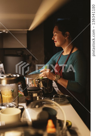 Woman Cooking in Kitchen with Joyful Expression Woman Cooking in Kitchen with Joyful Expression 136341180