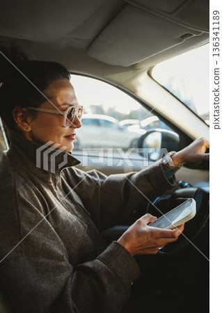 Woman Using Smartphone While Driving in Traffic 136341189