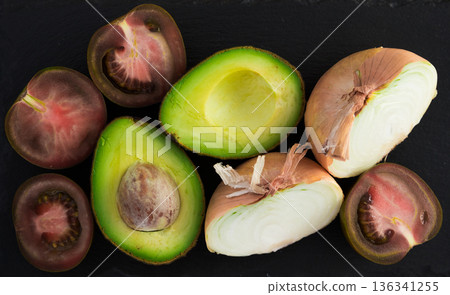 vegetables black tomatoes, avocado and onions on black stone board vegetables black tomatoes, avocado and onions on black stone board 136341255