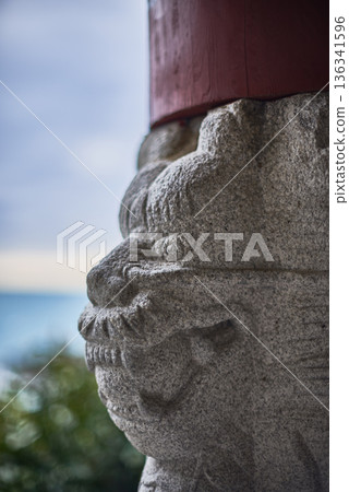 Stone guardian lion carving with blurred seaside background Stone guardian lion carving with blurred seaside background 136341596