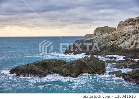 Rugged rocky coastline with waves under overcast sky Rugged rocky coastline with waves under overcast sky 136341610