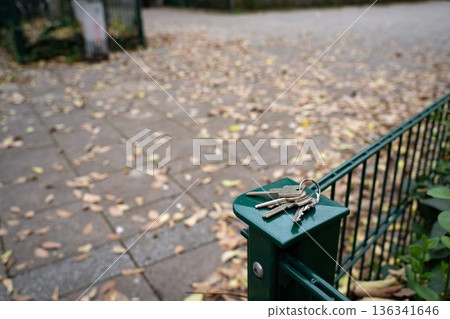 House keys resting on a garden fence in autumn. Everyday outdoor scene showing a personal item, representing routine, mobility, and seasonal life. 136341646