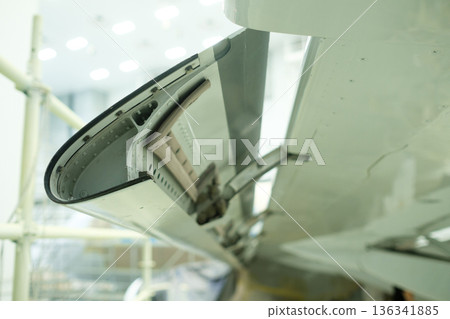 an aircraft wing flap mechanism showing the maintenance conditions of an aircraft with tools and equipment in the background during daytime 136341885