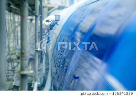 A technician applies blue paint to the aircraft fuselage at the maintenance center in the repair barn A technician applies blue paint to the aircraft fuselage at the maintenance center in the repair barn 136341889