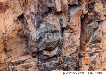 Volcanic rock texture with layered basalt fractures and mineral tones in detail 136341986