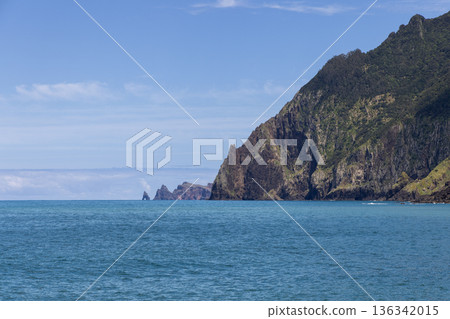 Atlantic cliffs and sea stacks near Porto da Cruz Madeira Portugal, calm blue water 136342015