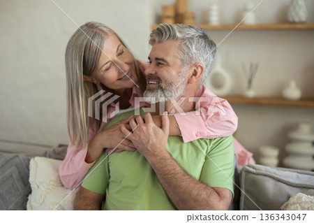 Loving couple embracing and sitting on sofa enjoying closeness 136343047