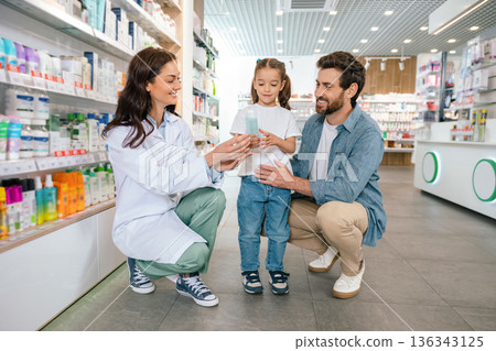 Pharmacist helping father and daughter choose product in pharmacy Pharmacist helping father and daughter choose product in pharmacy 136343125