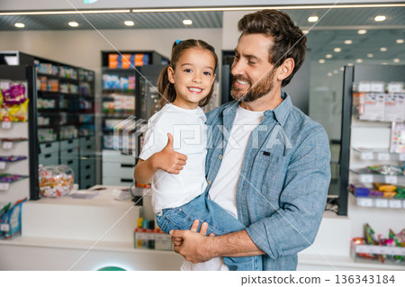 Dad holding little girl showing like gesture in drugstore 136343184